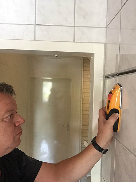 De muurscanner detecteert het hart van een houten stijl achter de betegeling.